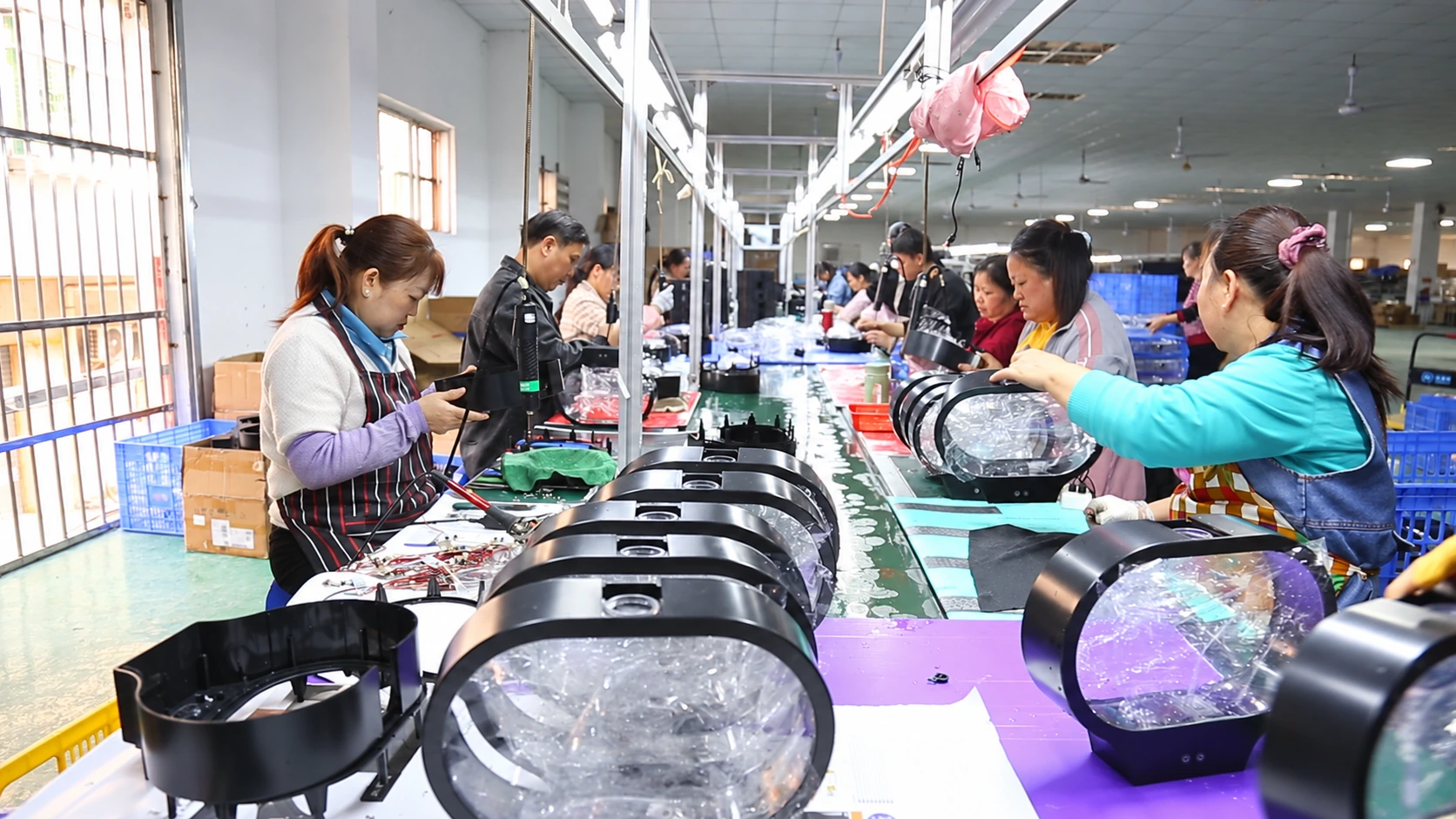Mingxiong employees assembling black oval jellyfish lamps along a workshop production line