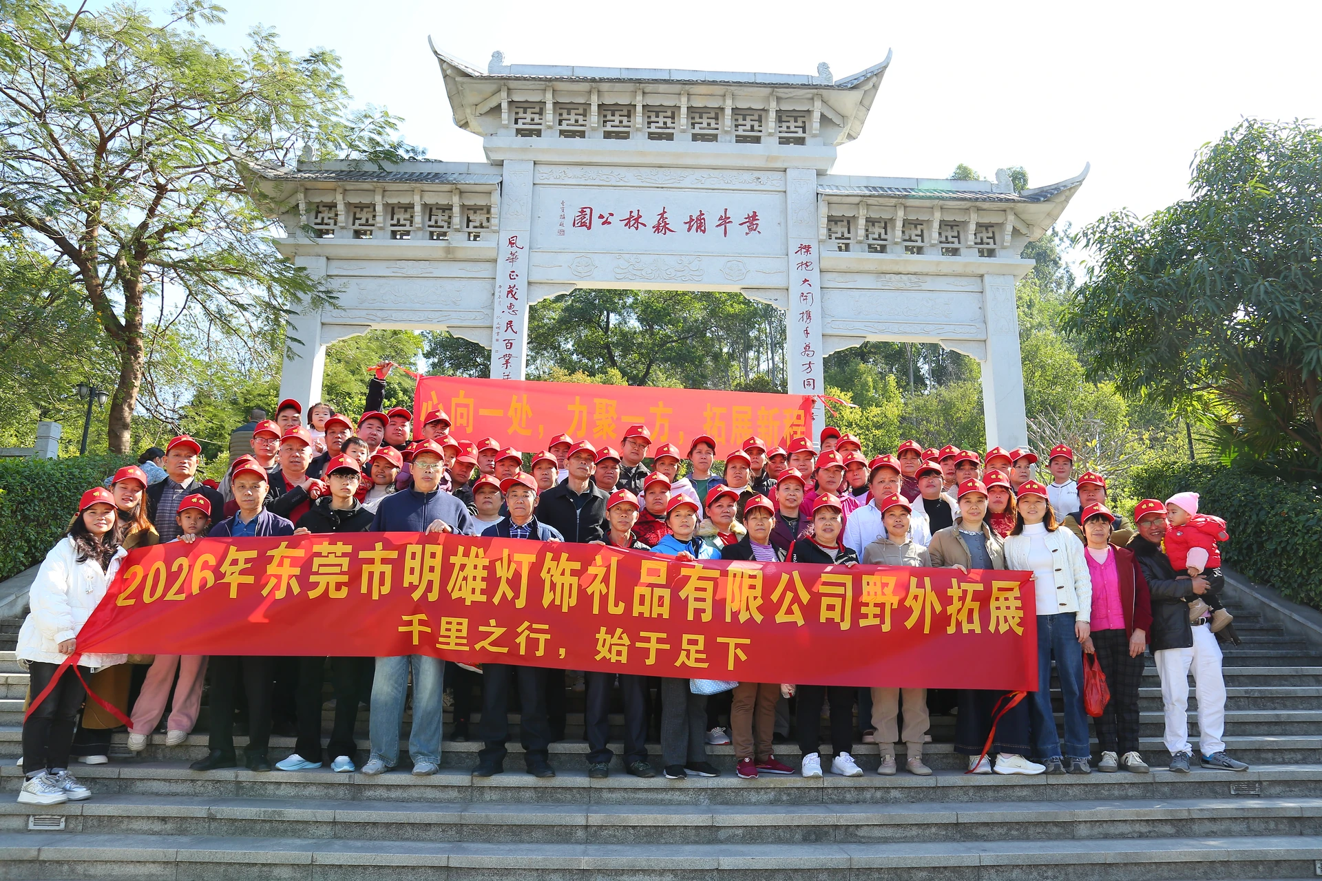 Mingxiong's team posing outdoors behind a red banner bearing the company name